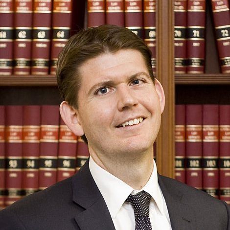 Close up photo of Mark Douglas standing in front of law books