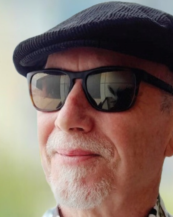 A close up photo of Tony Doyle wearing a hat and sunglasses