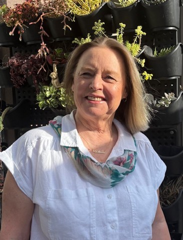 Close up photo of Michelle Howse with a vertical garden in the background