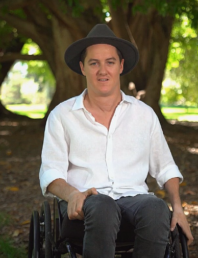 Photo of Charles Brice in his wheelchair with a tree in the background